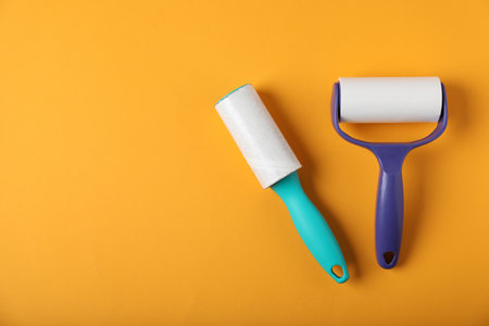 Two lint rollers on orange background, flat lay. Space for textの写真素材