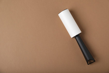 One lint roller on brown background, top view. Space for text