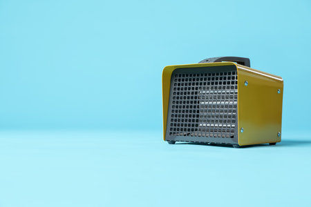 Electric fan heater on light blue background. Space for textの写真素材