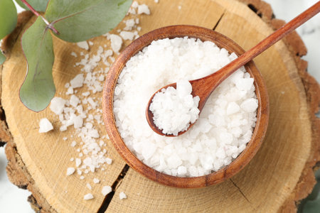 Sea salt in bowl, spoon and eucalyptus leaves on table, top viewの写真素材