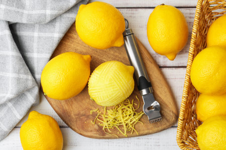 Lemon zest, fresh fruits and zester tool on light wooden table, flat layの写真素材