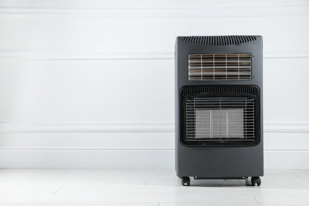 Electric heater on floor near light wall indoors. Space for textの写真素材