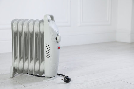 Electric heater on floor near light gray wall indoors. Space for textの写真素材