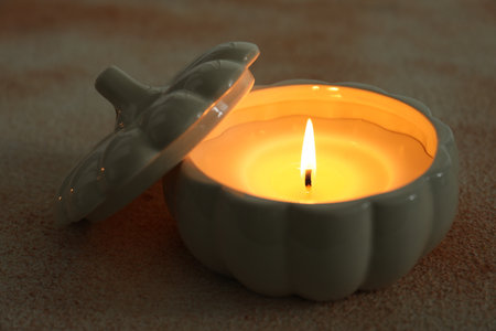 Burning pumpkin shaped candle on light table, closeupの写真素材