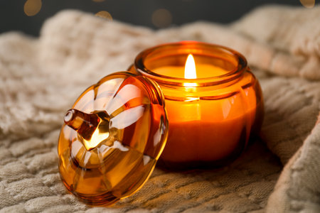 Burning candle on beige fabric against blurred lights, closeupの写真素材