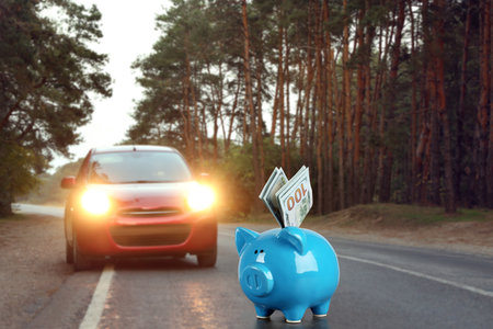 Piggy bank with dollars near car outdoors.の写真素材