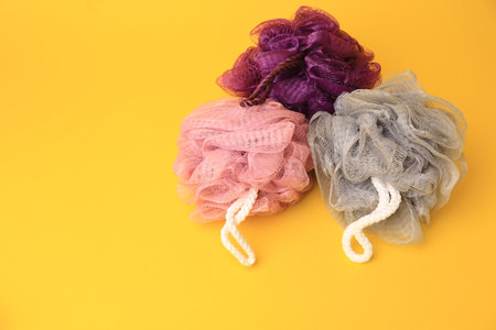 Colorful shower puffs on yellow background, space for textの写真素材