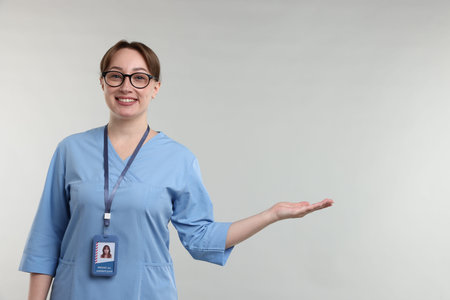 Professional nurse showing something on light gray background. Space for textの写真素材