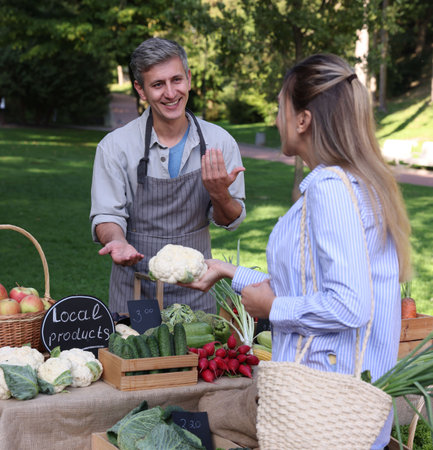 Woman choosing fresh vegetables from stall at farmer's marketの写真素材
