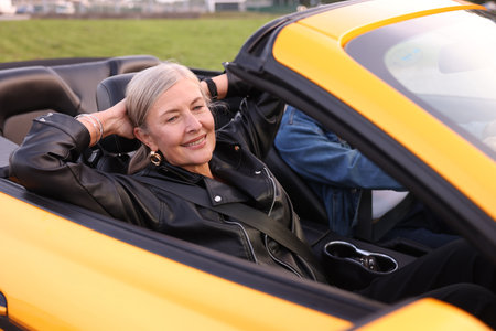 Stylish senior couple enjoying cabriolet ride outdoors, selective focusの写真素材