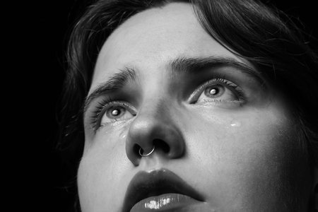 Sad woman crying on dark background, closeup. Black and white effect