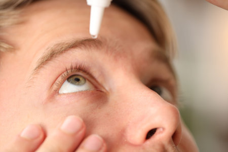 Man applying eye drops on light background, closeupの写真素材