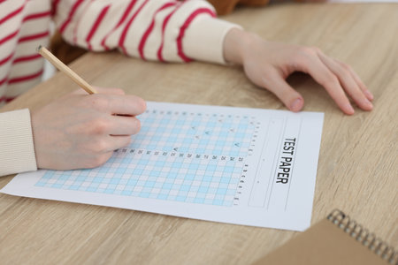 Student filling out answer sheet at wooden table indoors, closeup. Taking examの写真素材