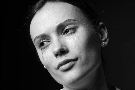 Sad woman crying on dark background, closeup. Black and white effect