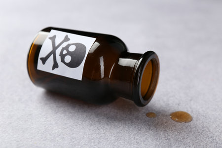 Overturned bottle of poison with warning sign on light gray table, closeupの写真素材