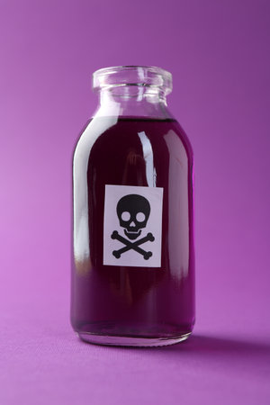 Bottle of poison with warning sign on purple background, closeupの写真素材
