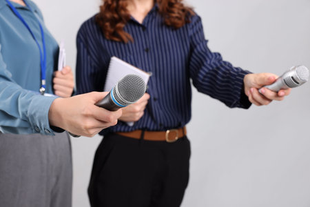 Journalists with microphones and notebooks on light background, closeup
