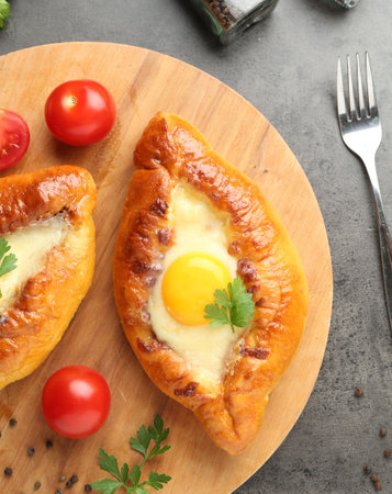 Tasty khachapuris with cheese and eggs served on gray textured table, flat layの写真素材