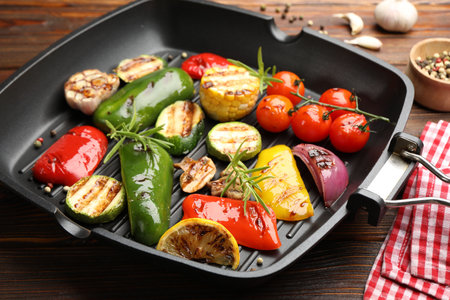 Pan with grilled vegetables and spices on wooden table, closeupの写真素材