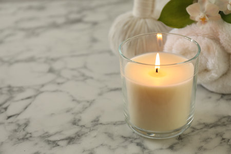 Beautiful spa composition with burning candle on white marble table, closeup. Space for textの写真素材