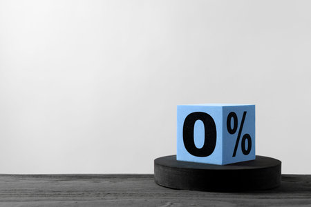 Cube with percent sign and 0 on table against light gray background