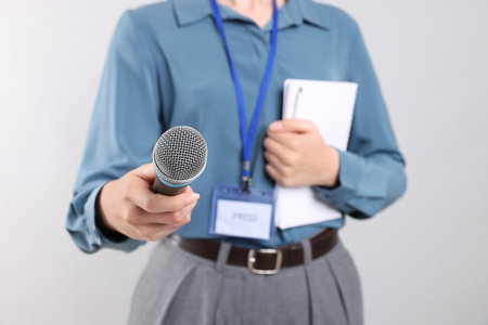 Journalist with microphone, notebook and pen on light background, closeupの写真素材