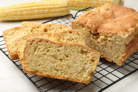Freshly baked cut cornbread on white marble table, closeup