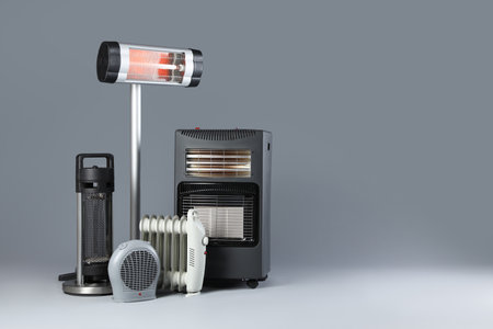 Different electric heaters on gray background. Space for textの写真素材