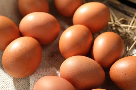 Raw chicken eggs and straw on table, closeup