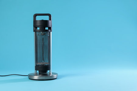 Electric heater on light blue background. Space for textの写真素材