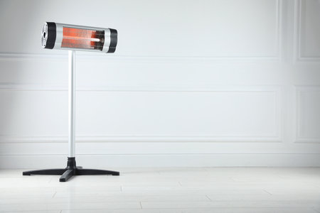 Infrared heater on floor near light gray wall indoors. Space for textの写真素材