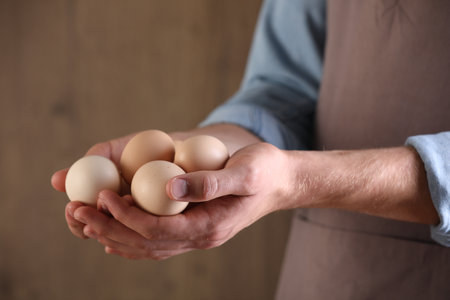Man with raw chicken eggs on blurred background, closeupの写真素材