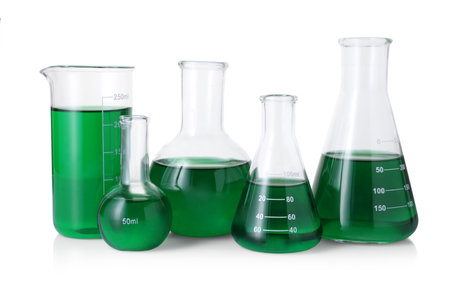 Different laboratory glassware with green liquid isolated on whiteの写真素材