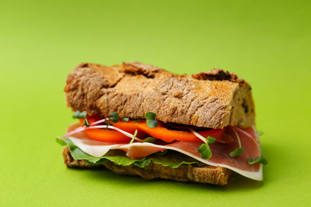 Tasty ciabatta sandwich on green background, closeup