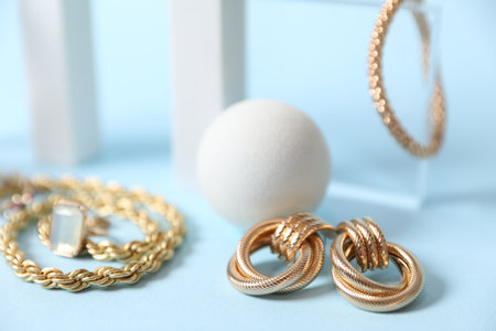 Stylish presentation of beautiful gold jewelry on light blue background, closeupの写真素材