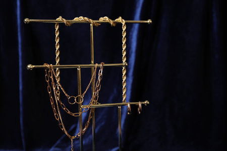 Stylish presentation of beautiful gold jewelry against dark blue fabric, closeup. Space for text