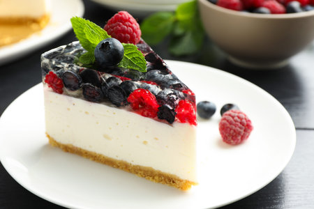 Piece of delicious cheesecake with berries and mint on black wooden table, closeupの写真素材