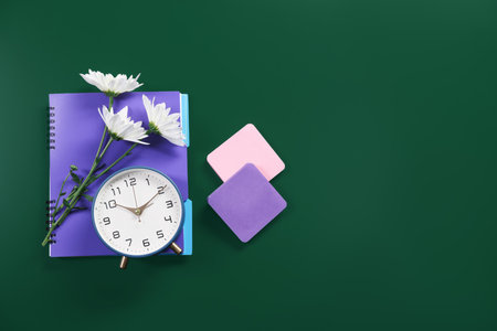 Happy teacher's day. Notebook, alarm clock, flowers and sticky notes on green background, flat lay. Space for textの写真素材