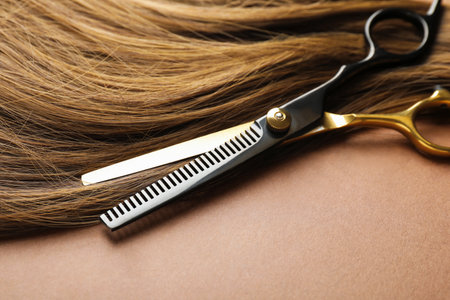 Beautiful hair and scissors on light brown background, closeupの写真素材
