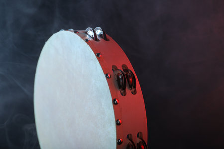 Tambourine in color light on black background with smoke, closeupの写真素材