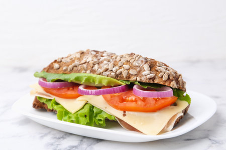 Tasty sandwich with cheese and vegetables on white marble table, closeupの写真素材