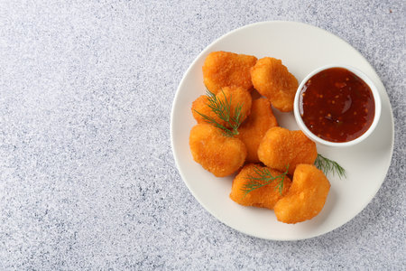 Tasty chicken nuggets with sauce on light gray table, top view. Space for textの写真素材
