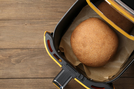 Freshly baked bread in air fryer on wooden table, top view. Space for textの写真素材