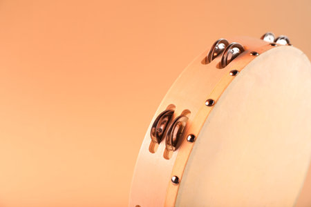 Tambourine on pale orange background, closeup. Space for textの写真素材