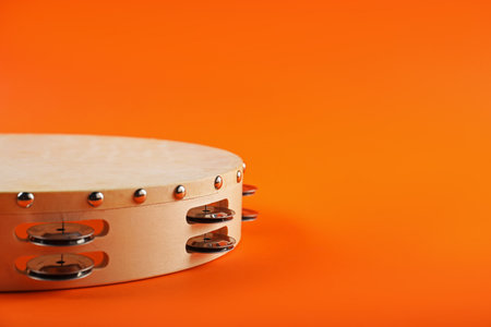 Tambourine on orange background, closeup. Space for textの写真素材