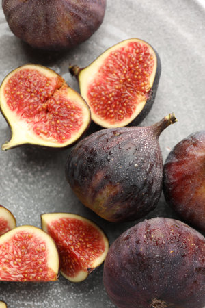 Whole and cut figs on gray table, flat lay