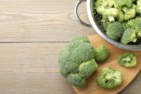 Fresh raw broccoli in colander on wooden table, top view. Space for textの写真素材