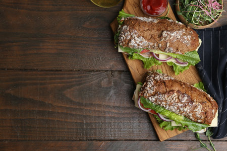Tasty sandwiches with cheese and vegetables on wooden table, flat layの写真素材