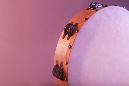 Tambourine in color light on pink background, closeup. Space for textの写真素材