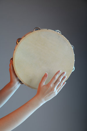 Woman playing tambourine on gray background, closeupの写真素材